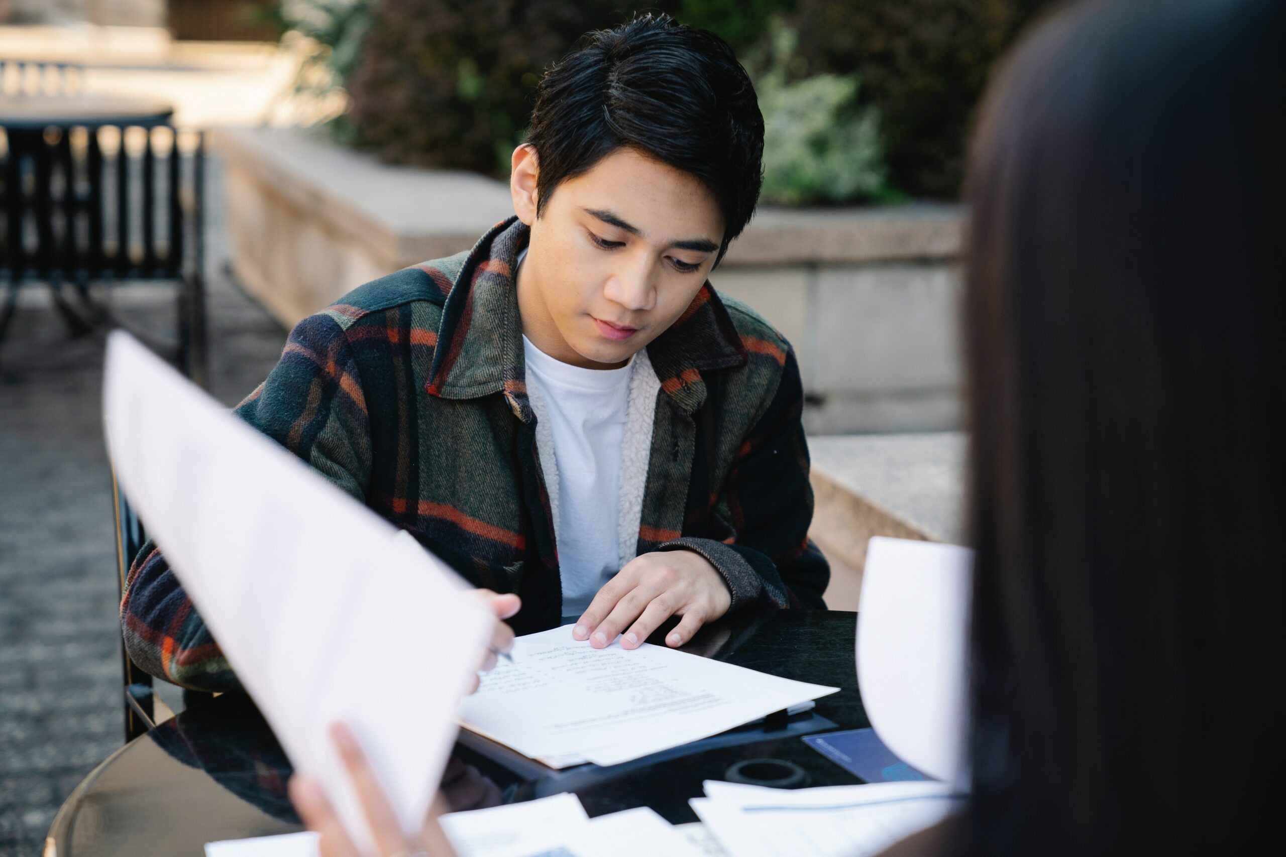 A young man working on school at an outdoor table.